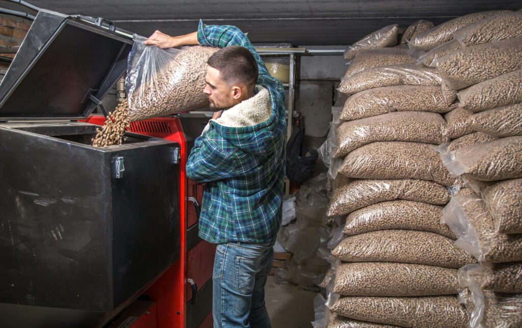 the man loads the pellets in the solid fuel boiler, economical heating